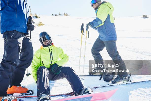 Laughing snowboarder hanging out with friends while riding on sunny winter afternoon