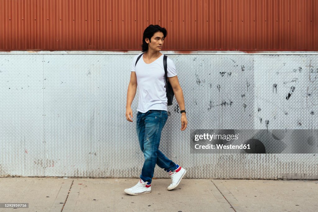 Man with a backpack walking on the sidewalk