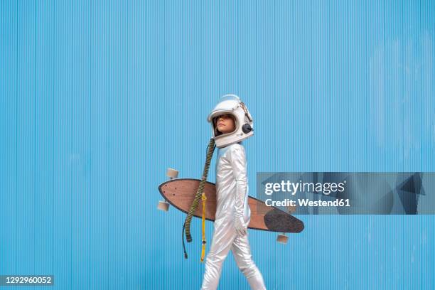 kid dressed as an astronaut with longboard - astronaut helmet stock-fotos und bilder