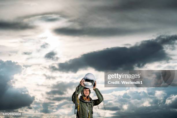 man posing dressed as an astronaut on a meadow with dramatic clouds in the background - heroes after dark stock pictures, royalty-free photos & images