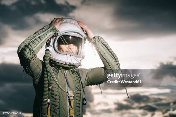 man posing dressed as an astronaut with dramatic clouds in the background - sun visor stock pictures, royalty-free photos & images