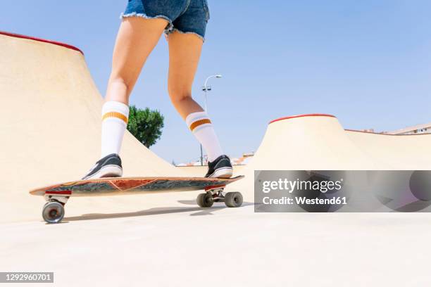 legs of young woman skateboarding on sports ramp against clear blue sky at park - legs in stockings stock pictures, royalty-free photos & images
