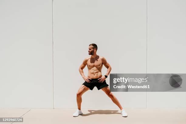 barechested male athlete stretching in sunshine - white shorts stock pictures, royalty-free photos & images
