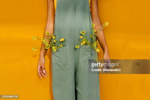 midsection of woman wearing overalls with yellow flowers in pockets - pocket ストックフォトと画像