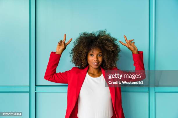 mid adult woman gesturing while standing against blue wall - blue blazer stock pictures, royalty-free photos & images