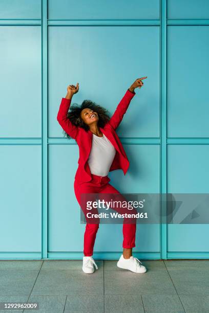 mid adult woman cheerfully dancing against wall - blue blazer stock pictures, royalty-free photos & images