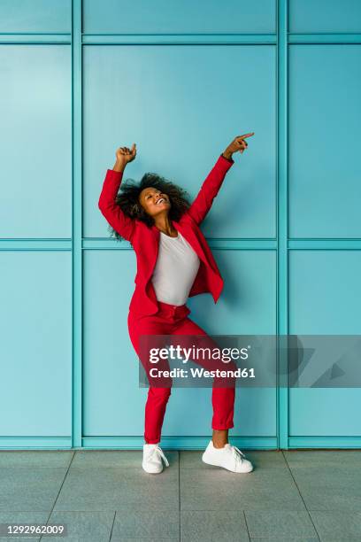 mid adult woman cheerfully dancing against wall - röd blazer bildbanksfoton och bilder