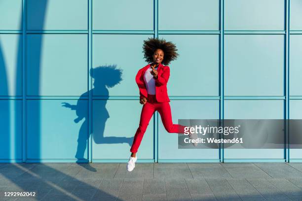 woman jumping cheerfully on sunny day - blue blazer stock pictures, royalty-free photos & images