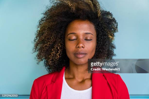 thoughtful woman with closed eyes standing against wall - blue blazer stock pictures, royalty-free photos & images