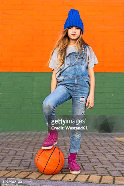 young girl with foot on basketball - children only stock-fotos und bilder