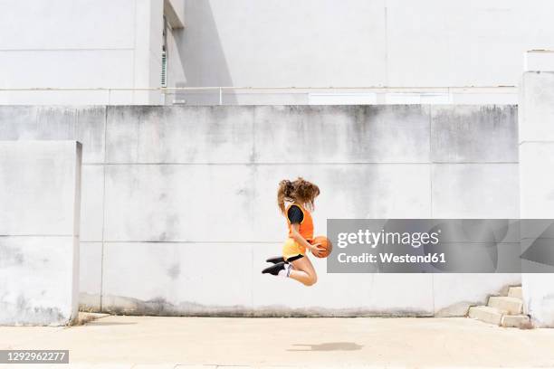 teenage girl jumping with basketball outdoors - teenage girl basketball photos et images de collection