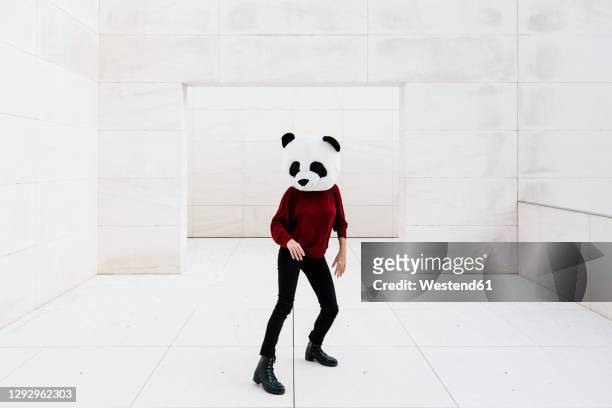 woman wearing panda mask standing on tiled floor against doorway - mask dance fotografías e imágenes de stock