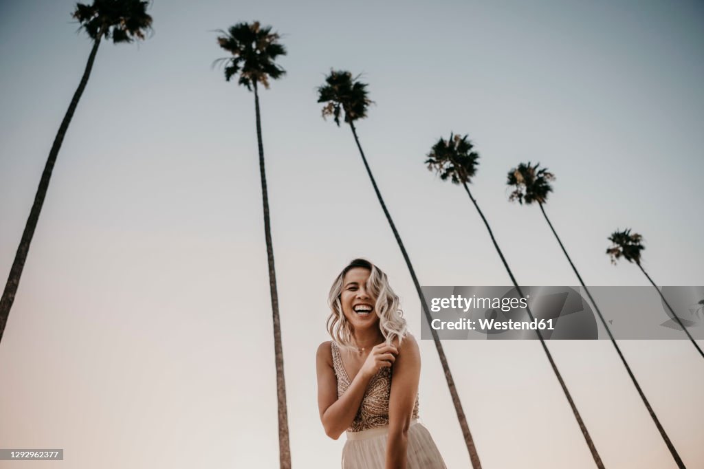 Low angle view of happy bride under palm trees