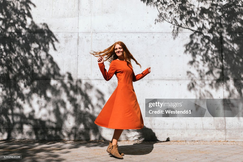 Happy woman dancing against tree shadow wall