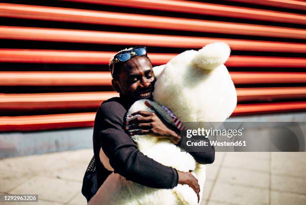 happy young man hugging huge teddy bear - big hug stock pictures, royalty-free photos & images