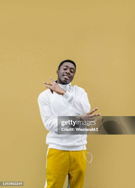 portrait of smiling young man showing victory sign - victory sign man stockfoto's en -beelden