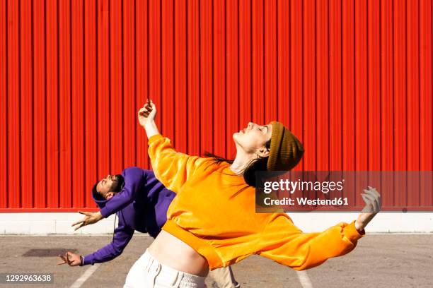 young man and woman performing in front of a red wall - outdoor entertaining stock-fotos und bilder