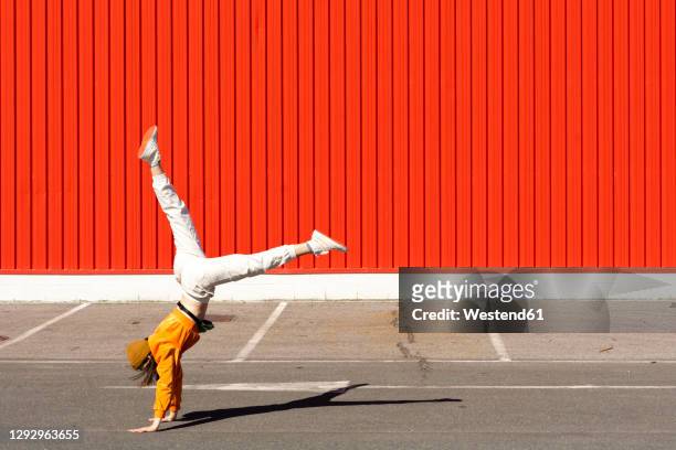 young woman doing a handstand in front of a red wall - handstand - fotografias e filmes do acervo