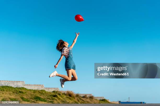 jumping young woman, letting go of a red ballon - barcelona free stock-fotos und bilder