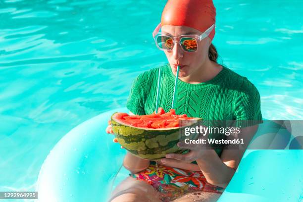 portrait of woman with floating tire and watermelon in swimming pool - crazy pool foto e immagini stock