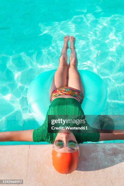 woman with floating tire leaning on poolside - swimwear fashion stock pictures, royalty-free photos & images