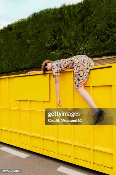 exhausted woman hanging over edge of yellow container - fainted stock-fotos und bilder