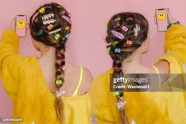 girl with hair clips in her braid holding smartphone woth happy and sad emoji - acessório de cabelo imagens e fotografias de stock