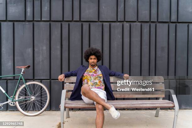 stylish man with bicycle sitting on a bench - black shorts stockfoto's en -beelden