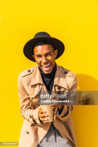 young man enjoying his take-out coffee - bunter mantel stock-fotos und bilder