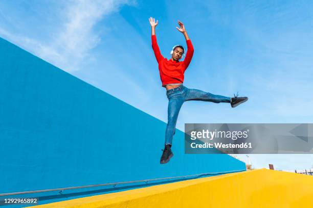 young man with headphones, listening music, dancing on yellow wall - fashion show bildbanksfoton och bilder