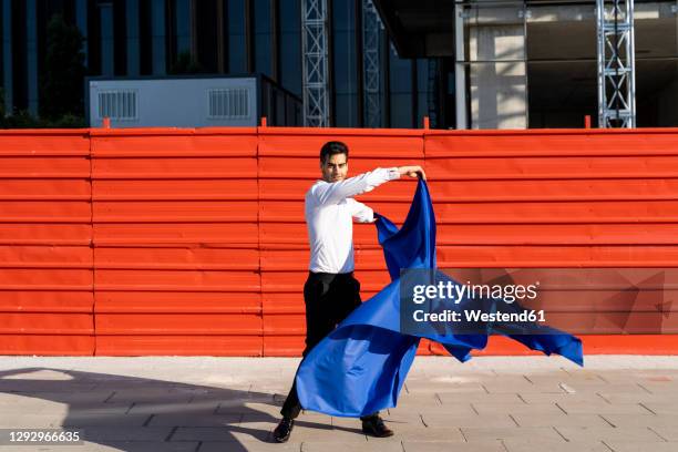 businessman swinging blue cloth on pavement in the city - human role stock pictures, royalty-free photos & images