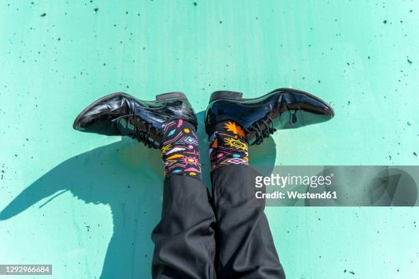 feet of businessman wearing colorful socks against green wall - colorful shoes stockfoto's en -beelden