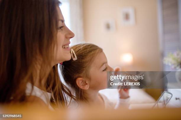 a mother and little daughter have fun while putting on make-up at home - fashionable family stock pictures, royalty-free photos & images