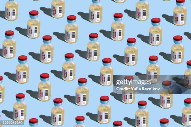 repeated vials with covid-19 vaccine on the blue background - covid 19 vaccine stock pictures, royalty-free photos & images