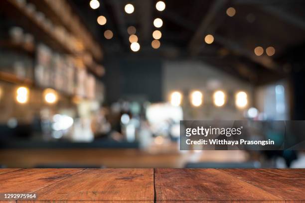 wood table top with blur of people in coffee shop or (cafe,restaurant )background - ristorante foto e immagini stock