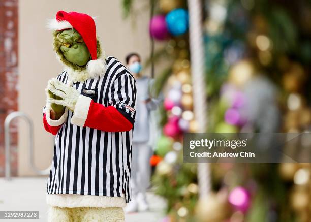 An employee of Foot Locker dressed as Grinch is seen posing at the entrance of the store on Robson Street on December 24, 2020 in Vancouver, Canada.