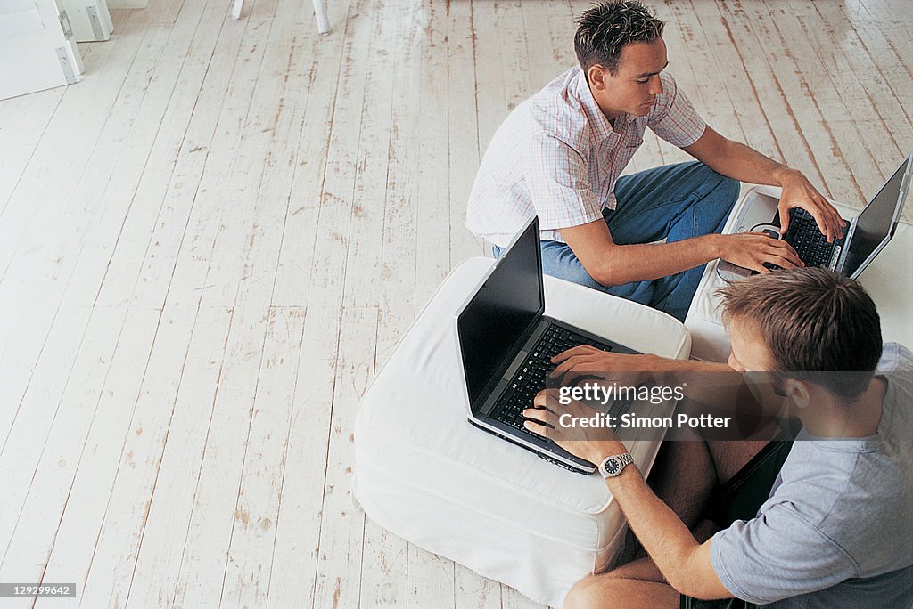 Men using laptops in living room