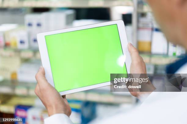 digital tablet with green screen in pharmcy - female pharmacist with a digital tablet imagens e fotografias de stock