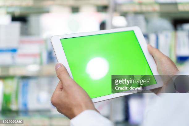 digital tablet with green screen in pharmcy - female pharmacist with a digital tablet imagens e fotografias de stock