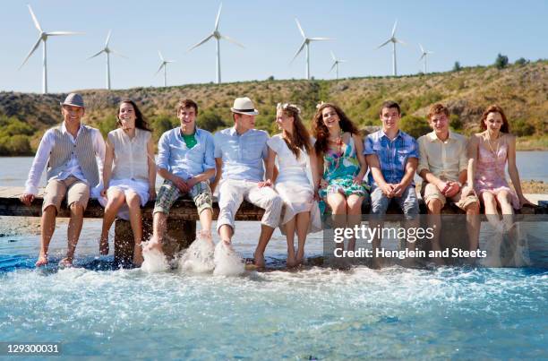 friends kicking water from deck - sitting-barefoot-on-dock stock pictures, royalty-free photos & images