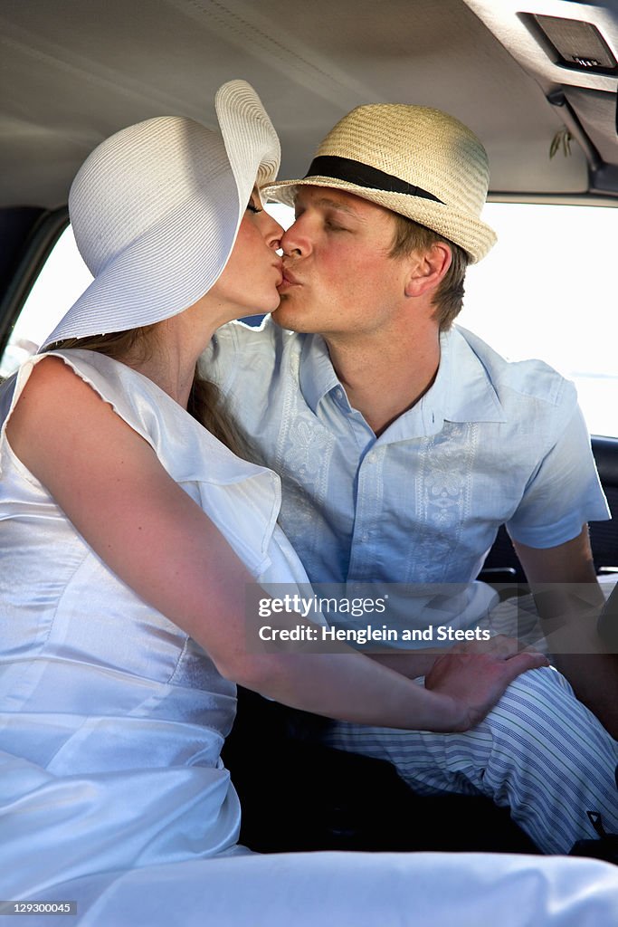 Newlywed couple kissing in car