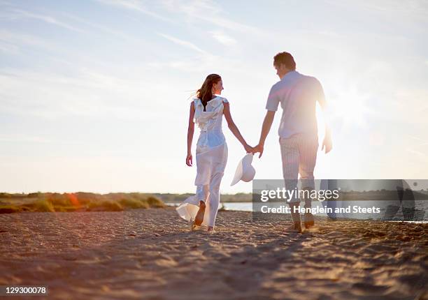 newlywed couple walking on beach - bride and groom back stock pictures, royalty-free photos & images