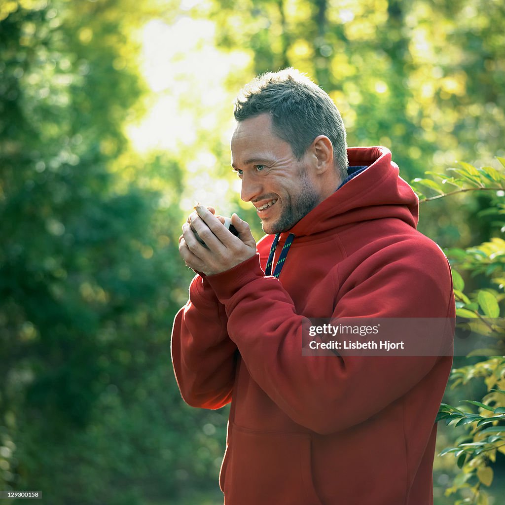 Homme de boire de tasse de café en forêt
