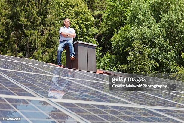 man standing on solar paneled roof - dach stock-fotos und bilder