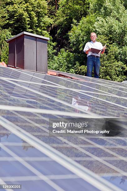 man standing on solar paneled roof - bavarian man in front of house stock-fotos und bilder