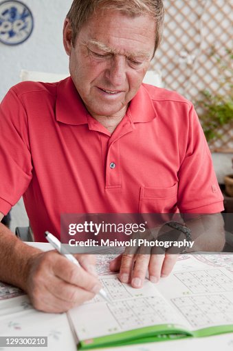 Older man completing sudoku puzzle Older man completing sudoku puzzle