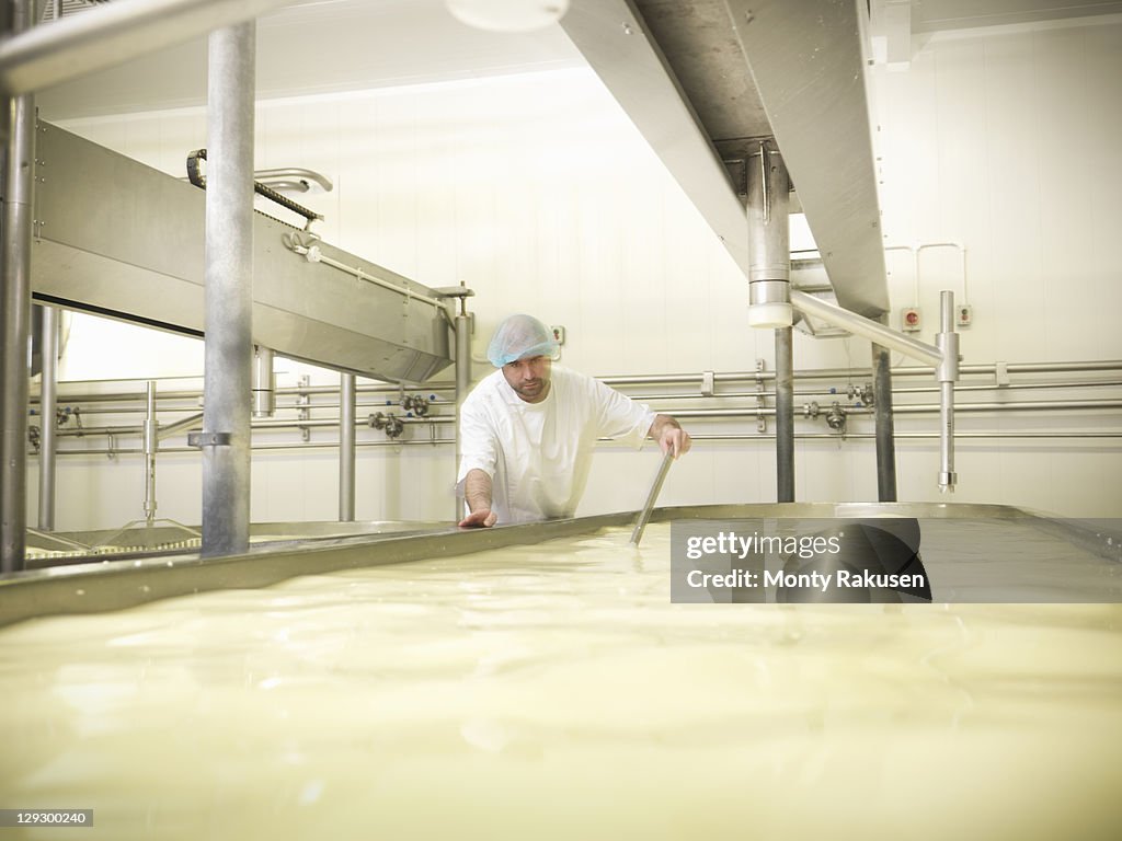 Worker stirring milk for cheese-making