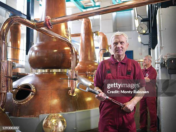 workers next to whisky stills in distillery - destillation stock-fotos und bilder