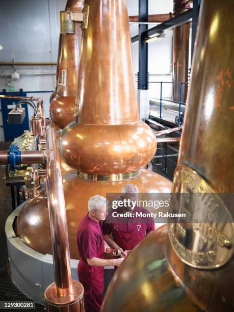 workers checking whisky stills in distillery - stills stock pictures, royalty-free photos & images