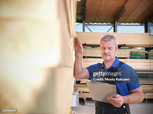 worker checking wooden planks in joinery - depósito de madeiras imagens e fotografias de stock